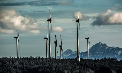 Das Foto zeigt Windkraftanlagen vor Bergen