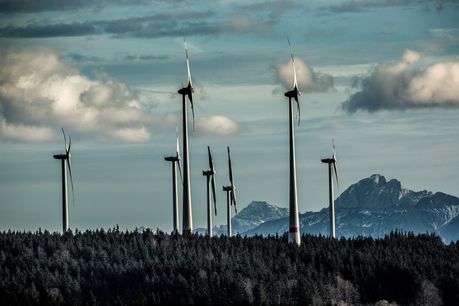 Das Foto zeigt Windräder vor Bergen