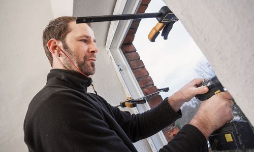 © Ingo_Bartussek_stock.adobe.com Das Foto zeigt einen Handwerker, der ein Fenster einbaut