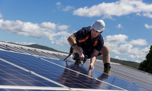 Das Foto zeigt einen Handwerker bei der Montage einer PV-Anlage